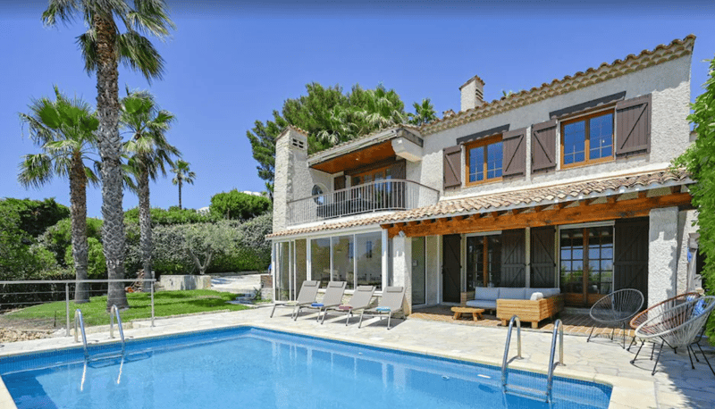 two-story house, swimming pool, covered terrace, garden furniture, palm trees, blue water