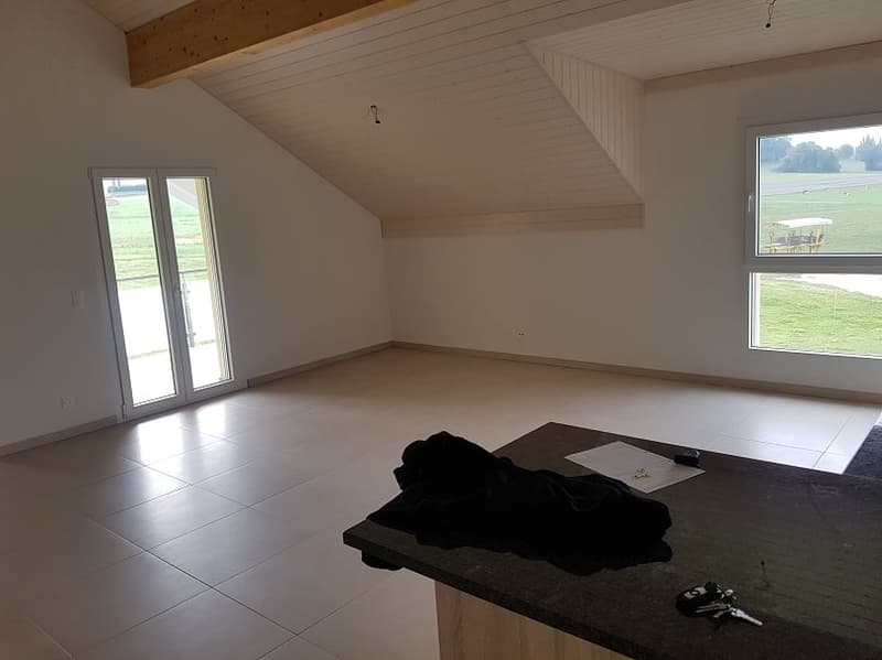 Empty room with large windows and sliding doors, offering a scenic view.