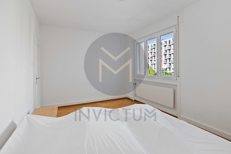 Chambre 2 / an empty bedroom in a small apartment with white sheets on the bed