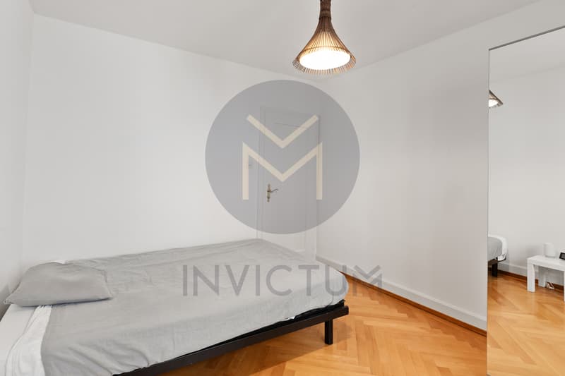 Chambre 1 / a bedroom in a small apartment with white walls and wooden floors