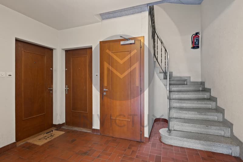 Entrée de l'immeuble  / a hallway with wooden doors leading to the entrance of a house