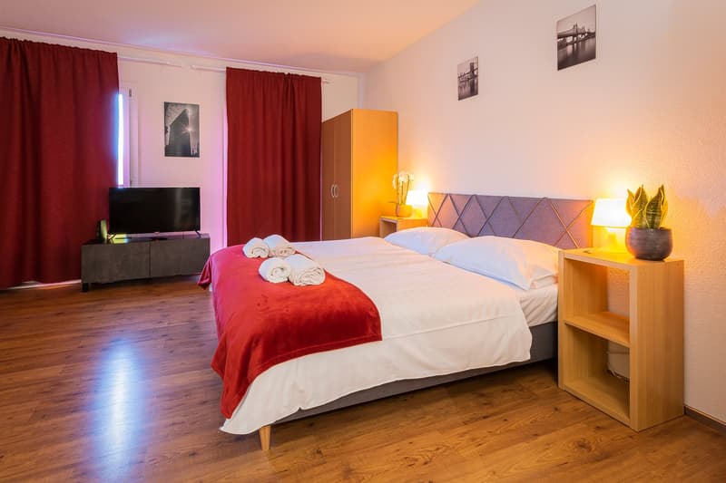 Double bed, pillows, blanket, nightstands, lamp, TV, cabinet, picture frame, curtains