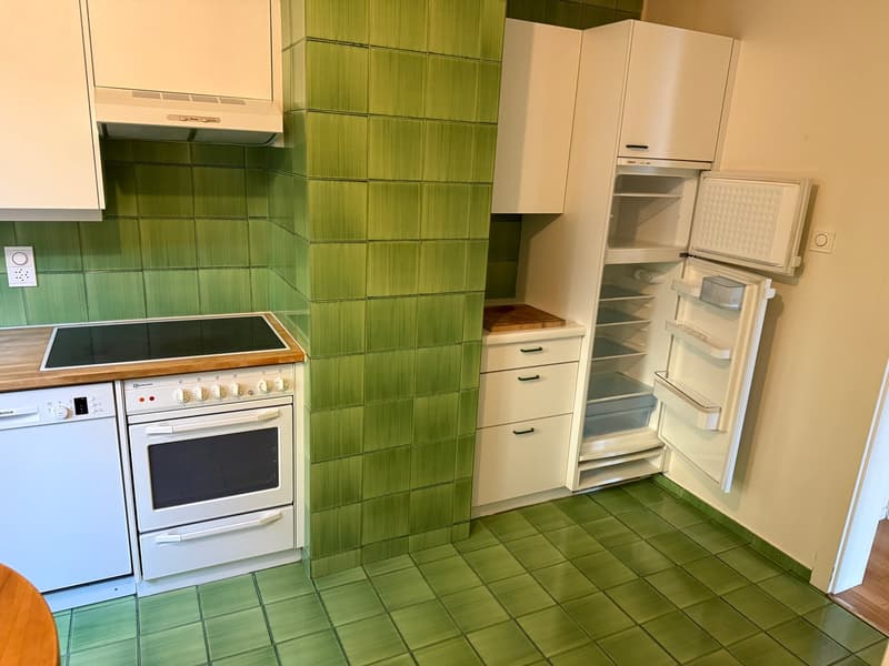green tiled kitchen with white appliances, open refrigerator, tiled floor, counter, stove, hood, sink, power outlet