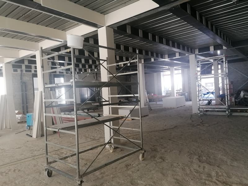 Under construction building, metal scaffolding, unfinished interior, exposed brick walls, large open space