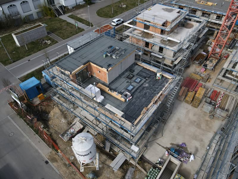 Aerial view of a construction site with multiple buildings under construction, scaffolding, and various construction materials.