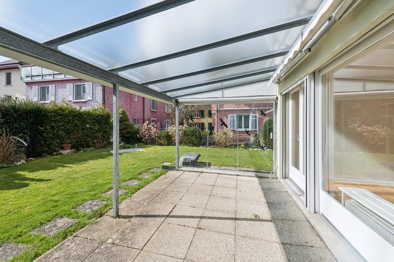 covered patio, glass doors, green lawn, bushes, metal poles