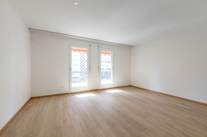 empty room, wooden floor, white walls, two glass doors leading to balcony, power outlets