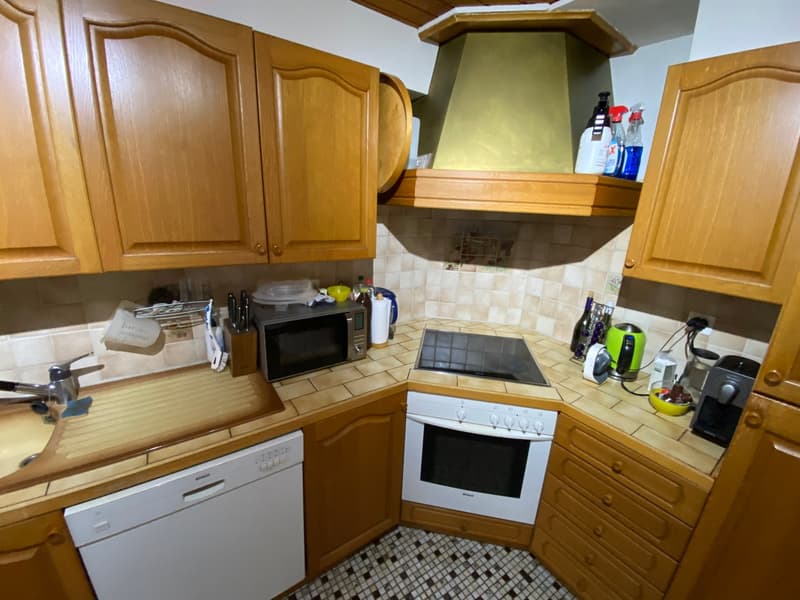 Wooden cabinets, tiled backsplash, white appliances, sink, dishwasher, microwave, stove, countertop, various kitchen utensils and appliances