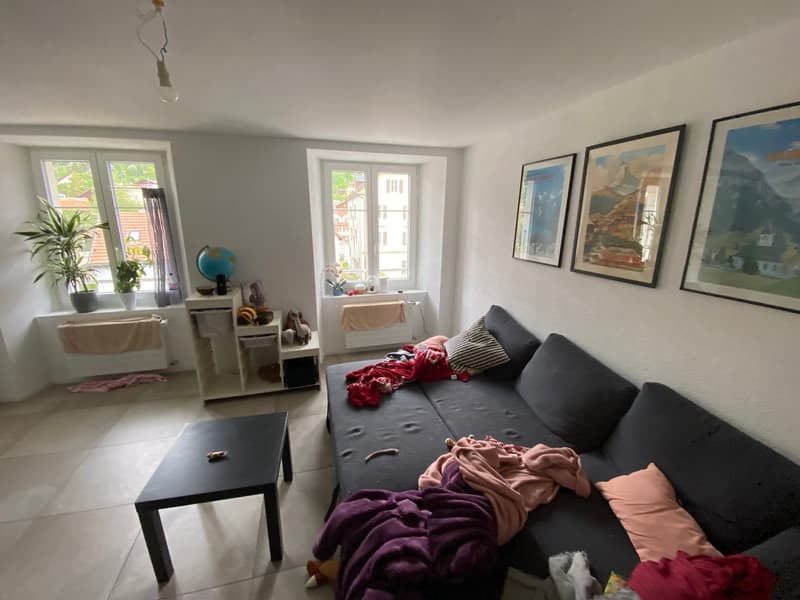 Living room with couch, coffee table, plants, and paintings on the wall