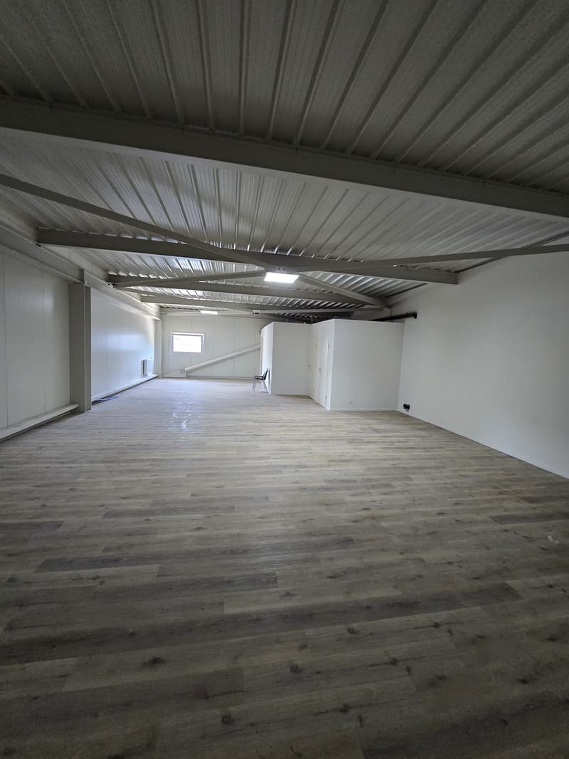 large open room, wooden floors, white walls, metal ceiling, small window