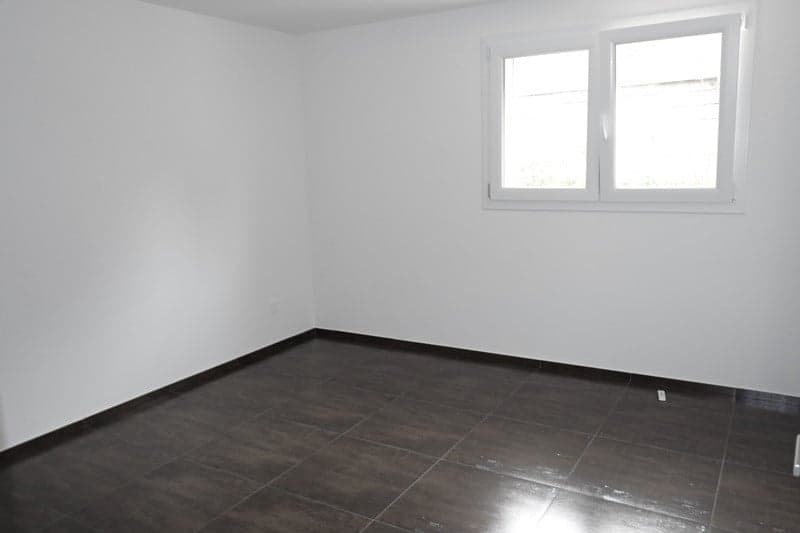 empty room with white walls, dark wooden tiled floor, and a window