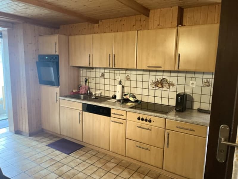 Spacious kitchen with wooden cabinets, tile flooring, and appliances including a washing machine and dishwasher