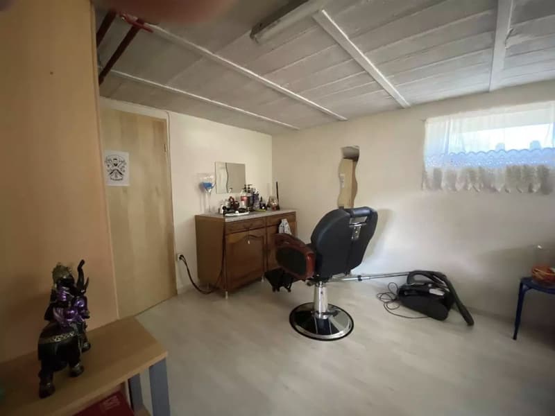 Bare room, barber chair, desk with cabinet, lamp, electrical outlet, statue, power outlet on wall, mirror, small table with bowl on right, open door to another room, window with white curtains