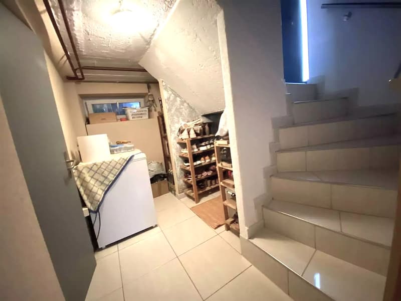 Small entrance with washing machine, tiled floor, white painted walls, stairs leading upstairs.