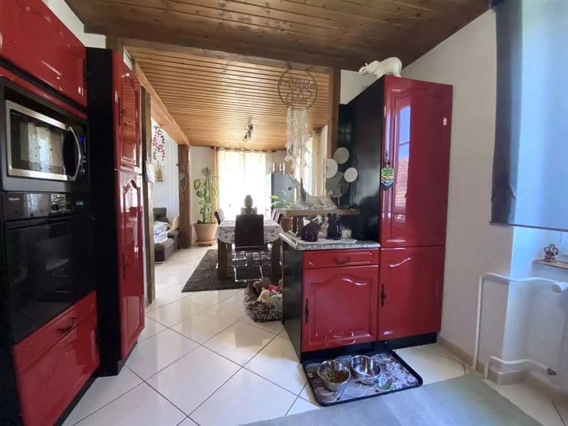 Red cabinets, white tiled floor, open dining area with table and chairs, oven, microwave, potted plant, dreamcatcher, dining table set up, bowl, and floor lamp.