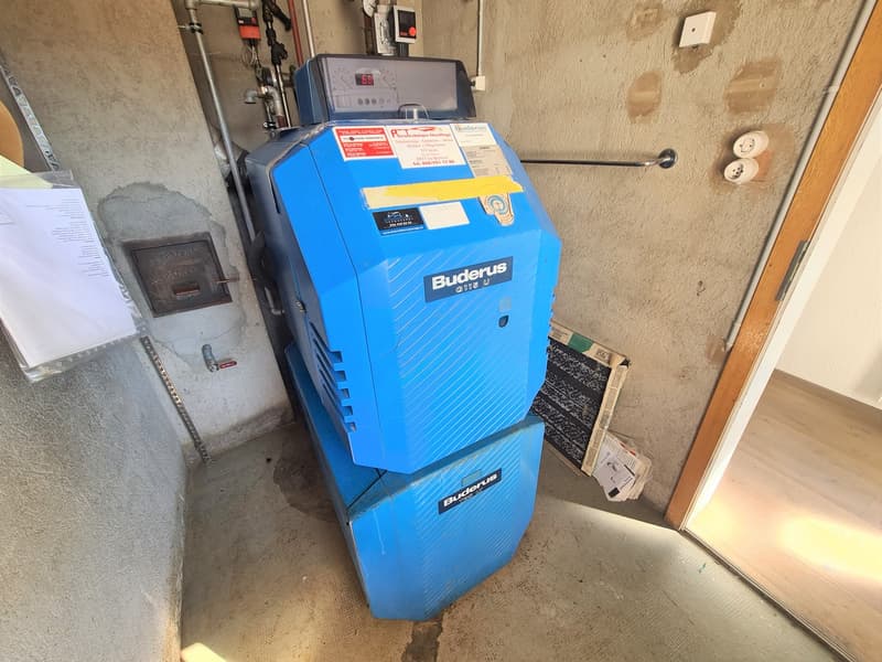 A blue Buderus heating system unit installed in a utility room or basement area.