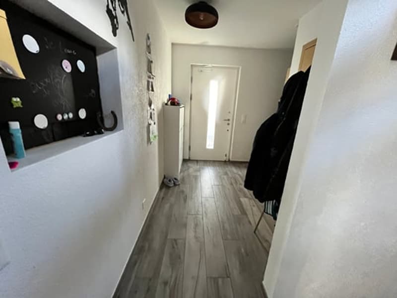 Hardwood flooring, white walls, coat rack, washing machine