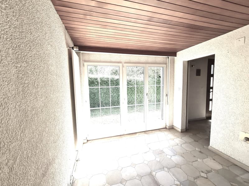 Enclosed patio or sunroom with large windows, wooden ceiling, and hexagonal tile flooring