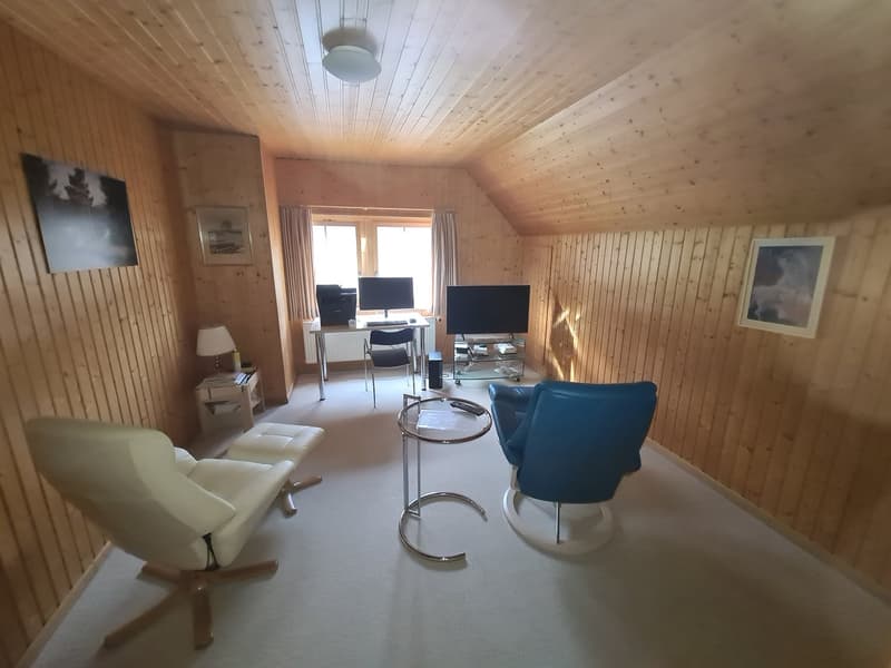 Wooden walls, ceiling, three swivel chairs, a desk, a television, a window with curtains