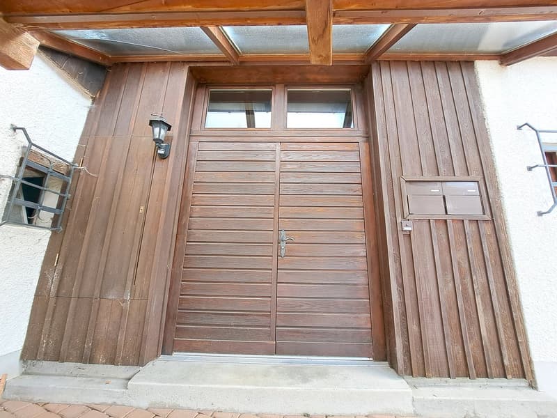 raised ground floor, wooden facade, double doors, glass windows, small lantern