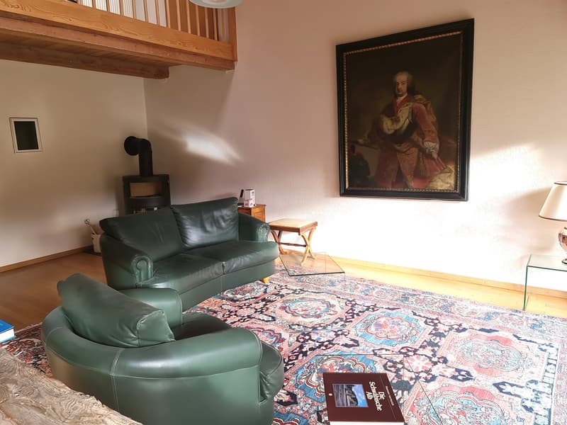 two green leather sofas, a rug, a fireplace, a large framed painting on the wall
