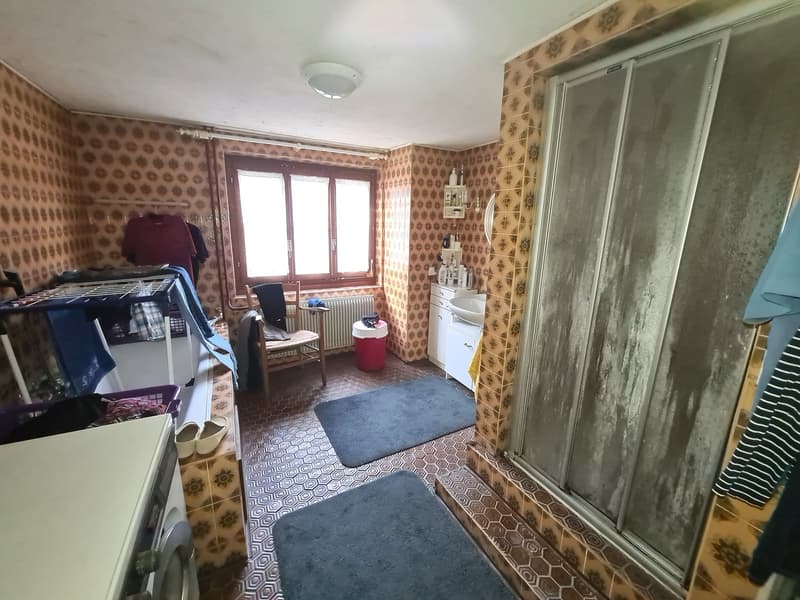 a small laundry room with a washing machine, drying rack, sink, and window