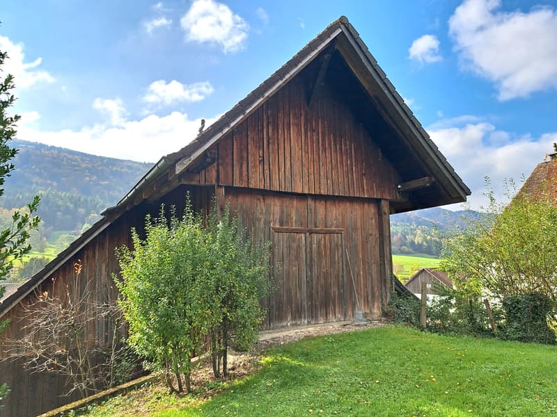 a wooden building, a large wooden door, and a green lawn
