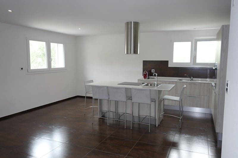 modern kitchen with gray chairs, kitchen island with sink, faucet, and stove, kitchen cabinets, windows