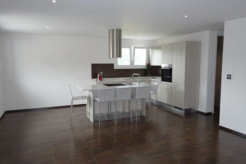 White cabinets, island with 6 chairs, white floor, sink with faucet, microwave, oven