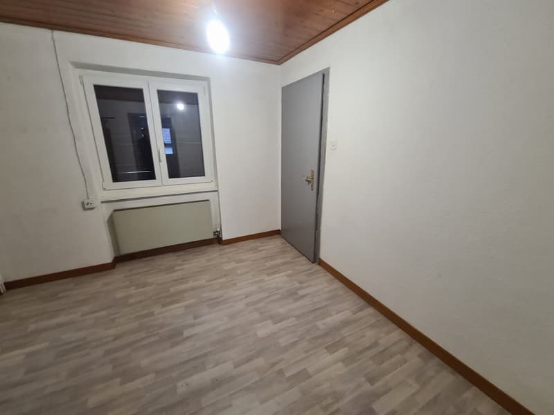 empty room with a window, heater, door, laminate flooring, and white walls