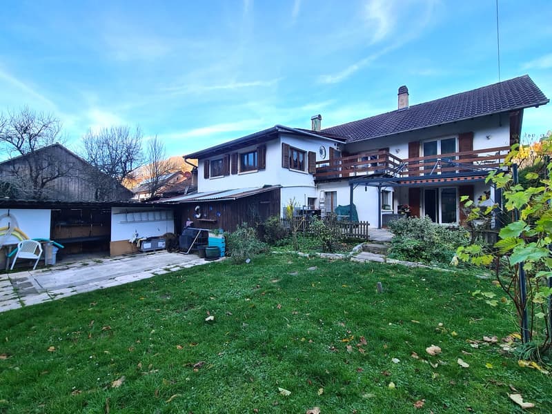 2 story house, brown roof, balcony on second floor, well-manicured lawn, garden, shed