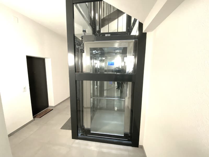 Glass elevator, modern interior design, white walls, white tile floor