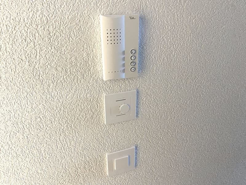 Two switches and a thermostat next to a doorbell