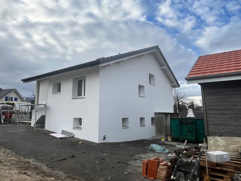 House with white exterior, new construction, several windows, scaffolding, storage bins, and brick pile