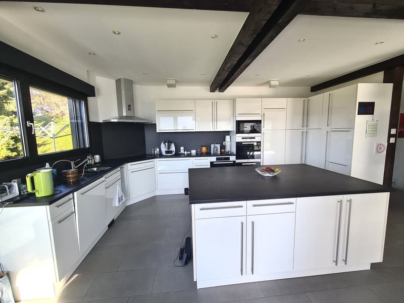 white cabinets, black countertop, integrated appliances, kitchen island, large window, kitchen tools