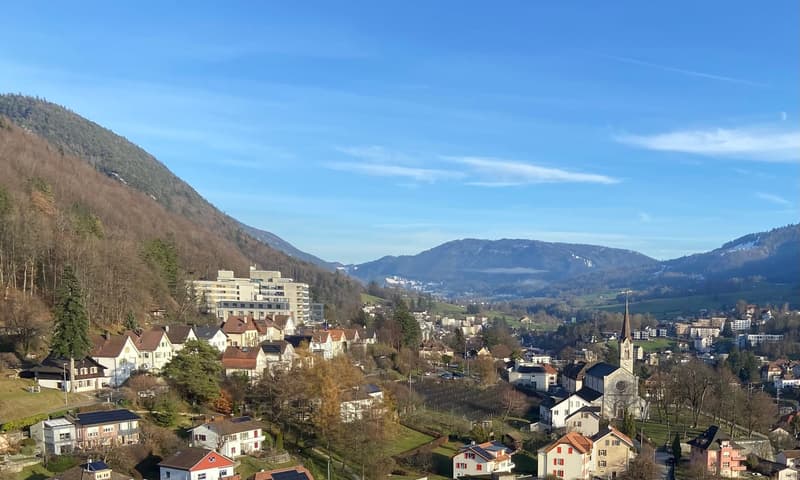 Aerial view of a town with houses, mountains, and a church in the background