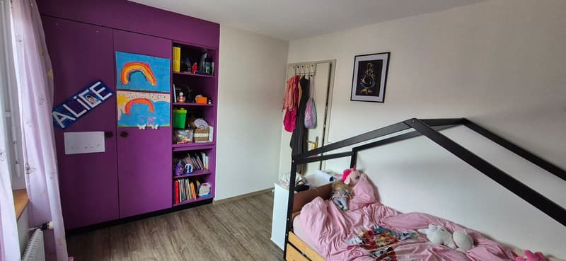 Children's bedroom with purple wardrobe, book shelf, small bed, toys, framed picture, curtain, white radiator