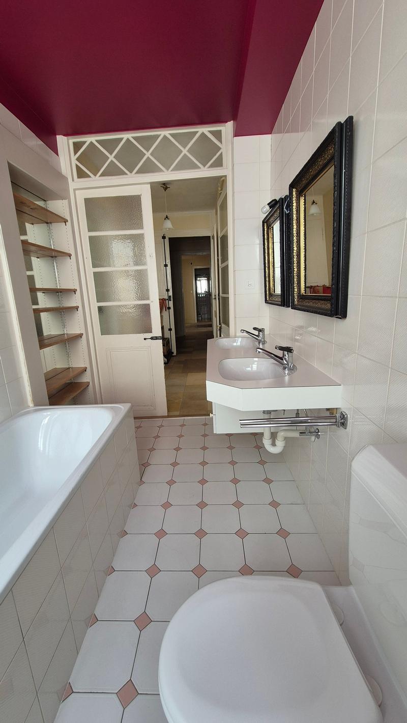 Bathroom with white bathtub, white sink, pink hexagonal tiles, a toilet, and a pink ceiling with two picture frames.