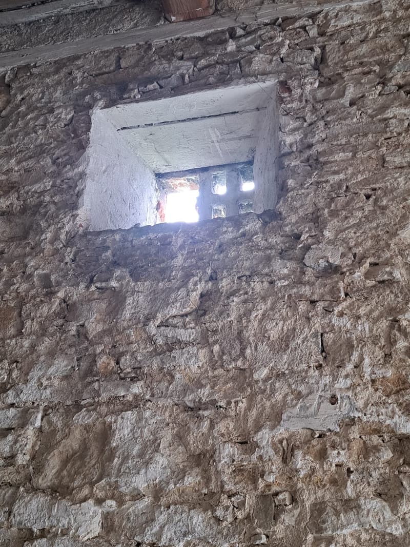 Rough textured stone wall with a window opening