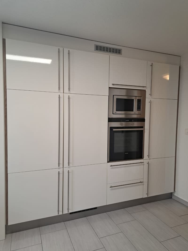 Modern kitchen with white cabinetry, stainless steel appliances, tiled floor, microwave, oven