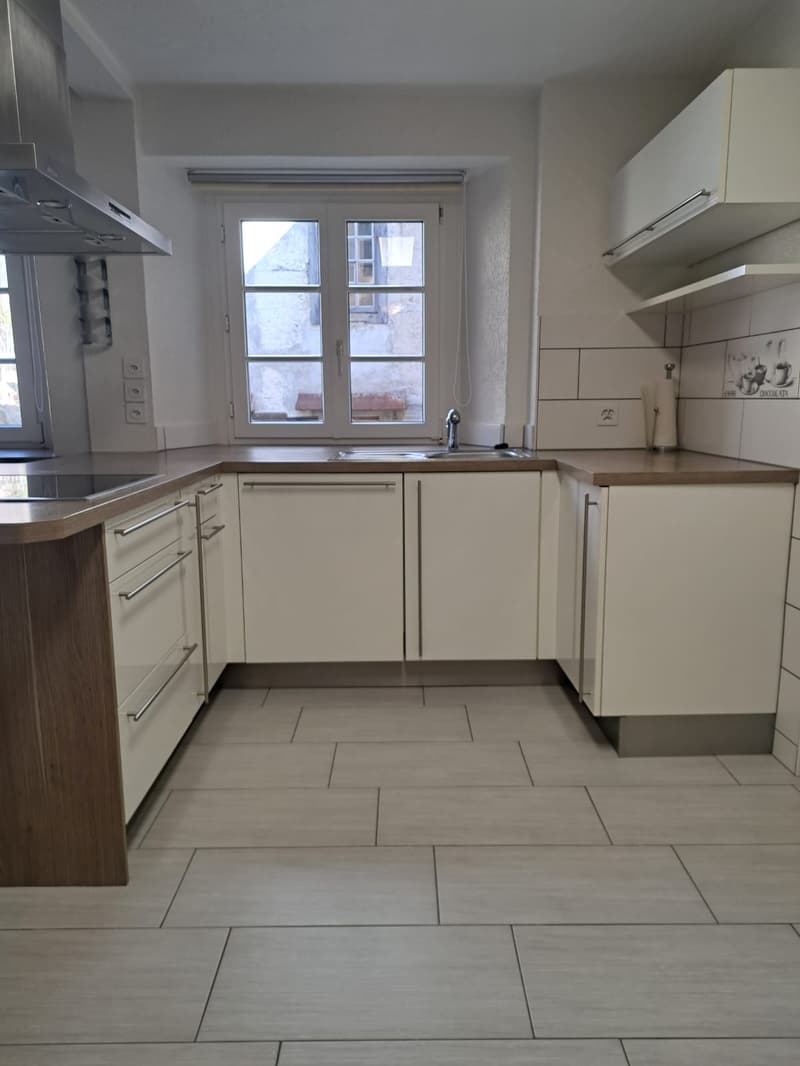 white kitchen, tile flooring, gas stove, stainless steel hood, modern cabinets, large window