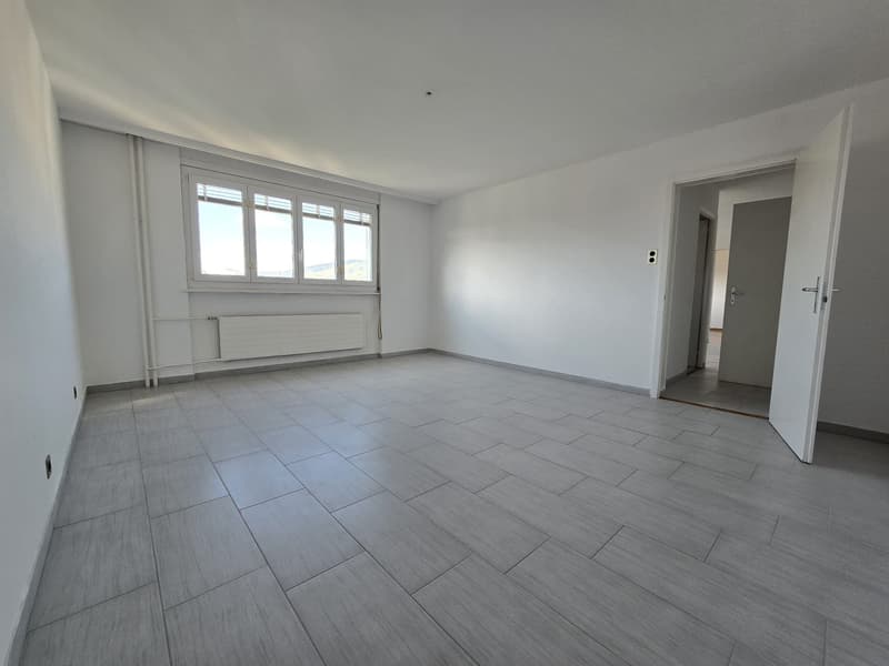 empty room with white walls, gray floor, a window, radiators