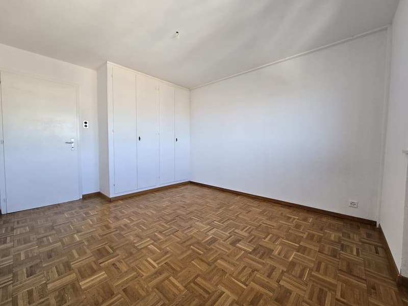empty room, white walls, wooden parquet flooring, white built-in wardrobe, white door, power outlet