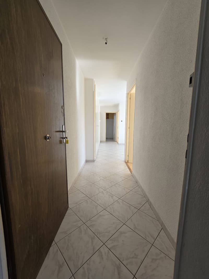 Empty hallway, tiled floor, white walls, doors, hallway leading to other rooms