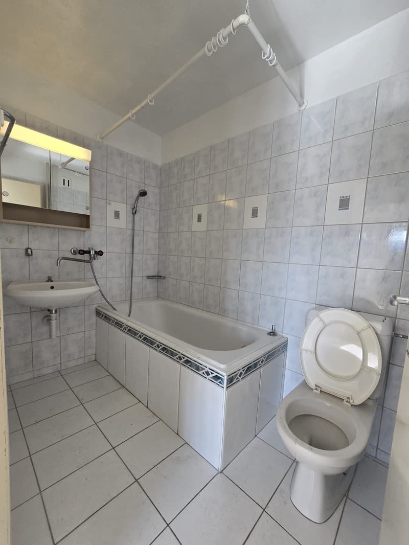 modern bathroom, white bathtub, toilet, sink, overhead shower, mirror