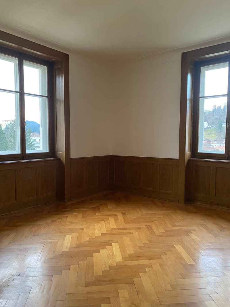 empty room with 2 large windows, wooden floor, white walls