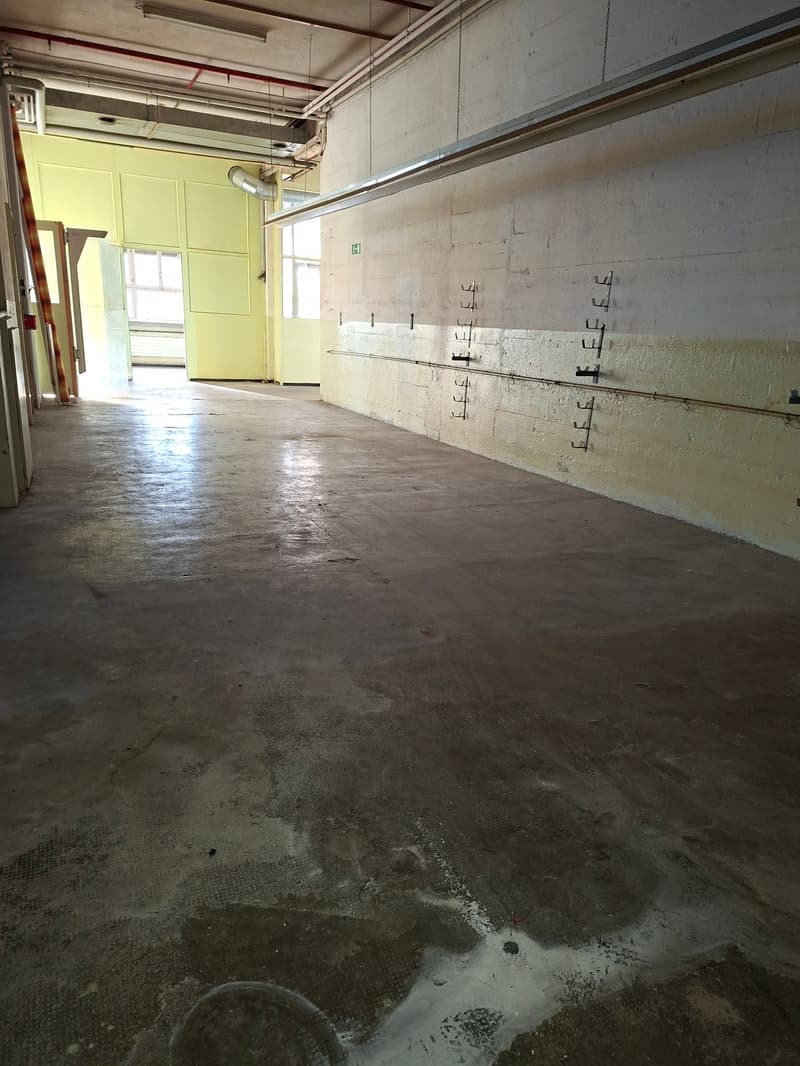 empty room with white walls and yellow walls, large windows, metal pipes on the ceiling and walls