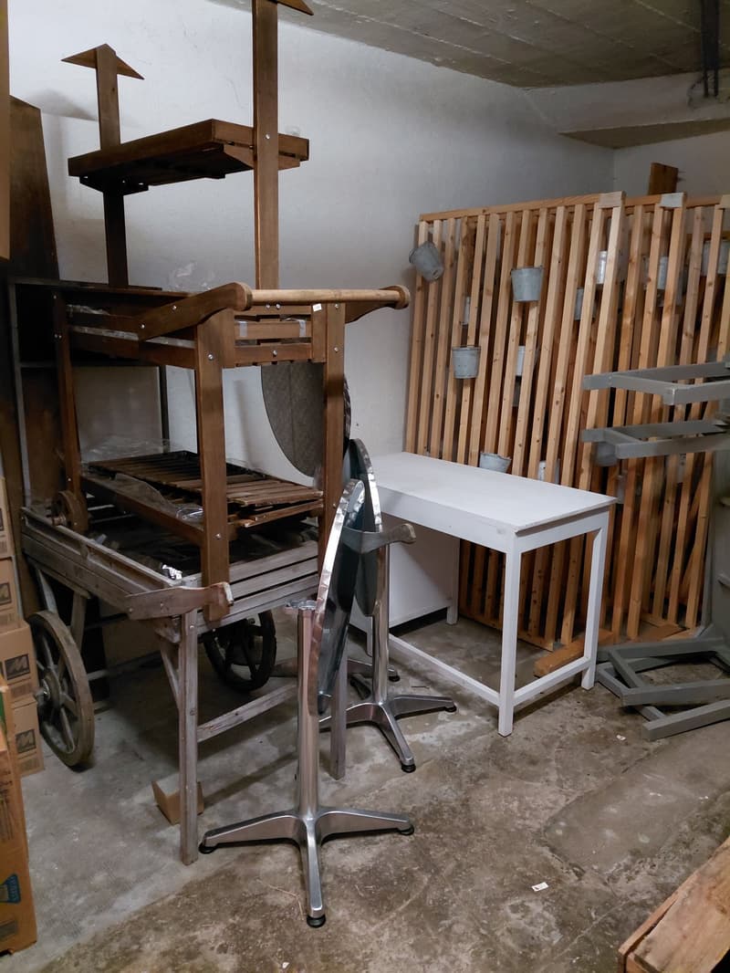 industrial space with various items including a cart, desks, buckets, metal structures, and storage boxes