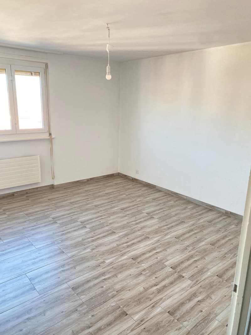 empty room, white walls, wooden floor, window, radiator, light fixture