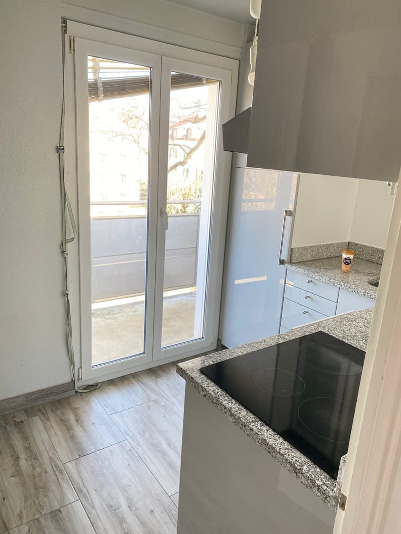 kitchen with balcony, granite countertop, black induction hob, white cabinets, sliding glass door